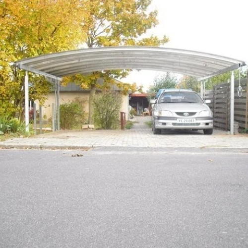Dobbelt carport foran villa med bred parkeringsplads