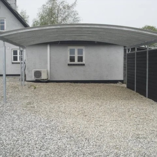 Dobbelt carport med sideafskærmning på grusbelagt indkørsel