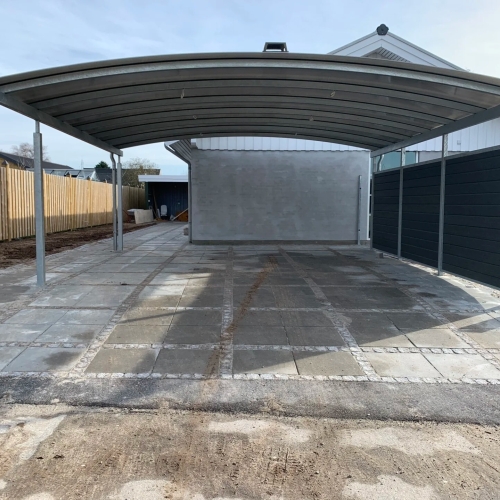 Dobbelt carport med parkeret bil på bred indkørsel