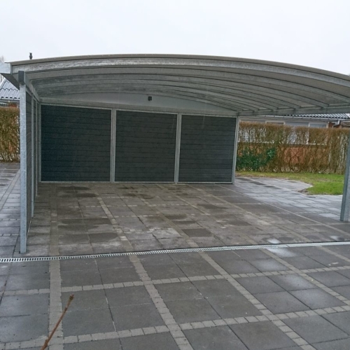 Carport med skur i moderne design med buet tag og mørk komposit beklædning.