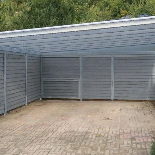 Carport med skur og sidebeklædning i moderne grå trædesign.