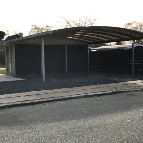 Carport med skur og buet tag ved moderne parcelhus.