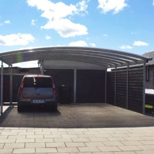 Carport med skur og plads til bil på flisebelagt indkørsel.