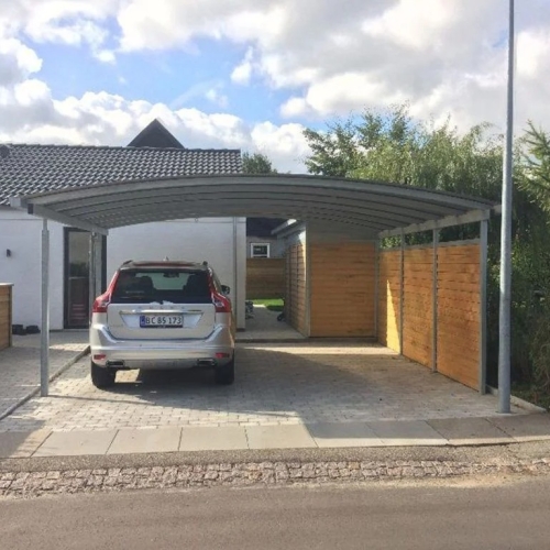 Carport med skur og træbeklædning ved villa med indkørsel.
