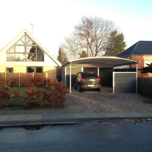 Carport med skur og parkeret bil foran moderne villa i Brønshøj.
