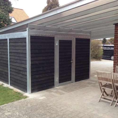 Moderne carport med skur og overdækket terrasse i mørk træbeklædning i Horsens.