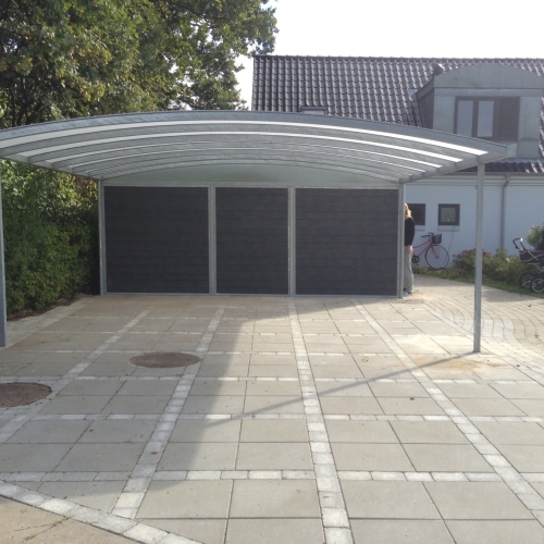 Bred carport med skur og galvaniseret stålkonstruktion foran bolig i Hvidovre