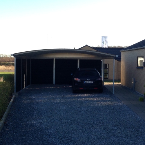 Dobbelt carport med skur og buet tag ved moderne parcelhus i Ringsted