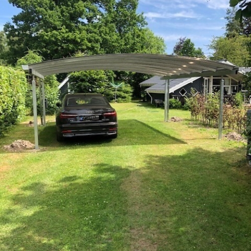 Dobbelt carport på græsareal med plads til flere køretøjer