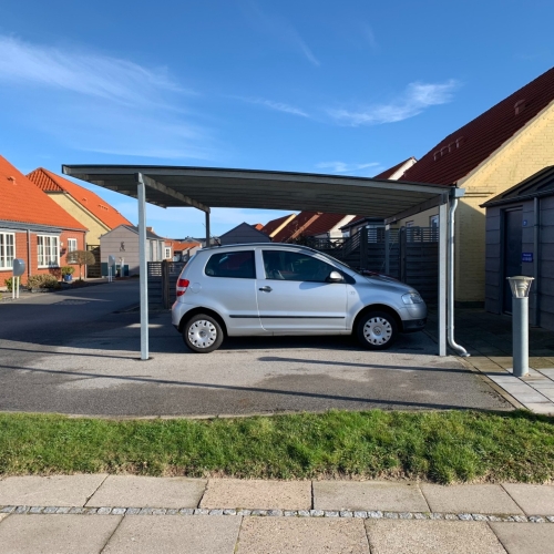 Dobbelt carport med fladt tag og bilparkering ved bolig