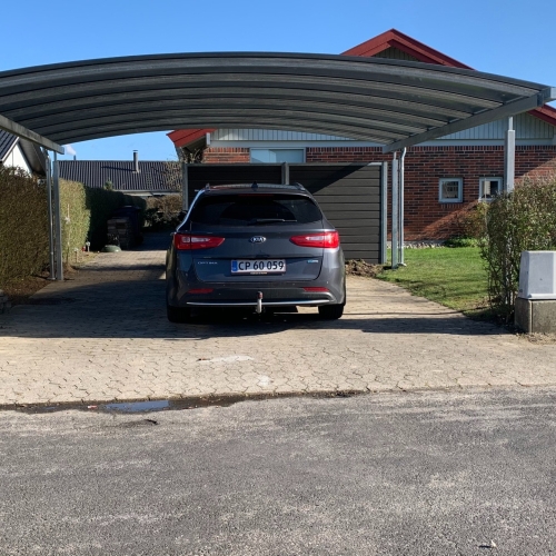 Stor dobbelt carport med buet tag og mørke sidepaneler