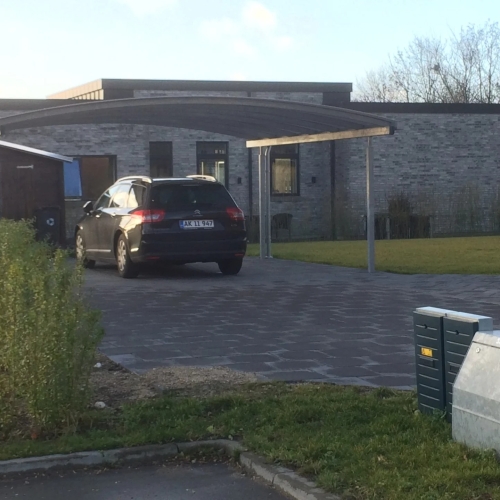 Dobbelt carport med bil foran moderne murstenshus i Klarup