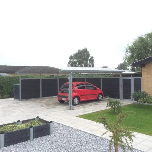 Dobbelt carport med sidevægge og moderne belægning i Vadum
