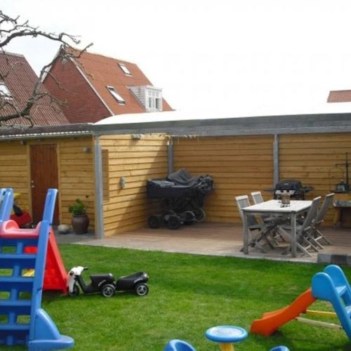 Terrasseoverdækning i træbeklædt have med spiseplads