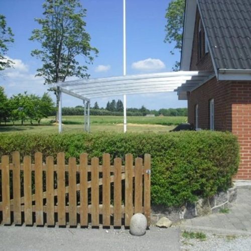 Buet terrasseoverdækning ved murstenshus i landlige omgivelser