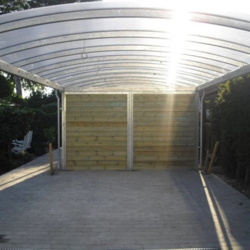 Carport med skur i lyst træ og buet tag
