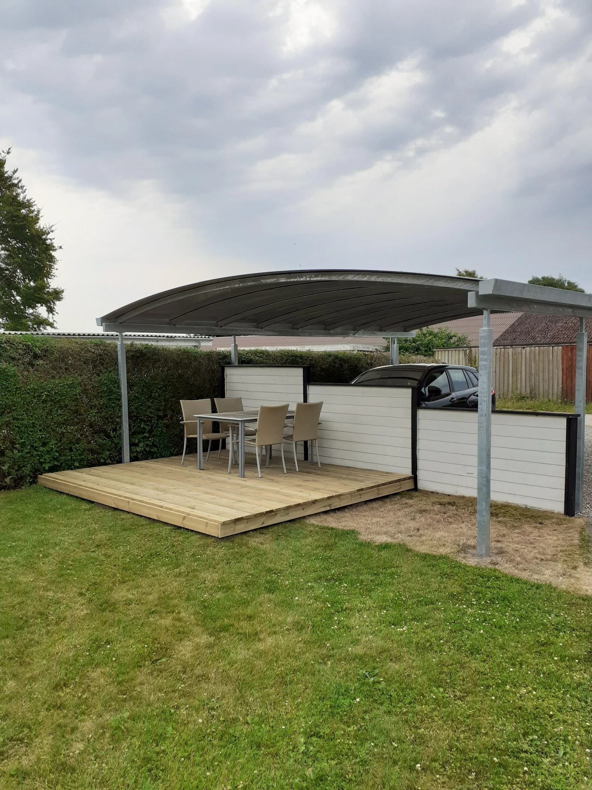 Dobbelt carport med overdækket terrasse og træterrasse i haven